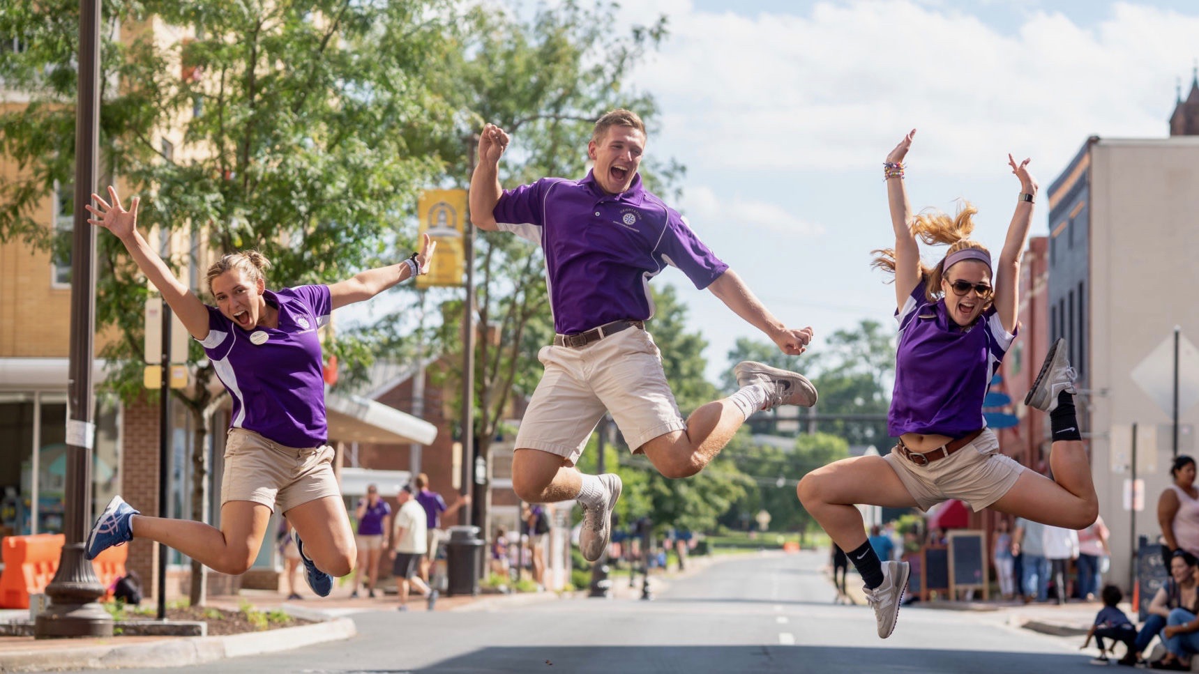 Three James Madison University students jumping up in the middle of the main street in downtown Harrisonburg.